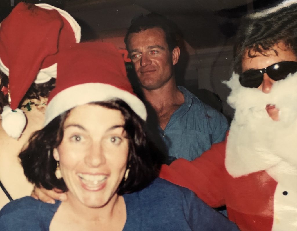 Jacinta grinning at camera while wearing a santa hat, at a Christmas party